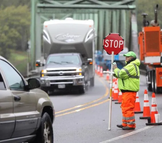 Certified flagger managing traffic with stop sign during lane closure to ensure work zone safety and compliance