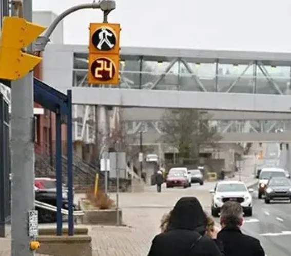 Pedestrians waiting at a crosswalk with countdown signal at a busy urban intersection