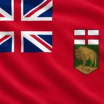 Flag of Manitoba: red background (Red Ensign) with the Union Jack in the upper left canton and Manitoba's shield of arms on the right, depicting the Cross of St. George above a green field with a standing bison on a rocky outcrop.